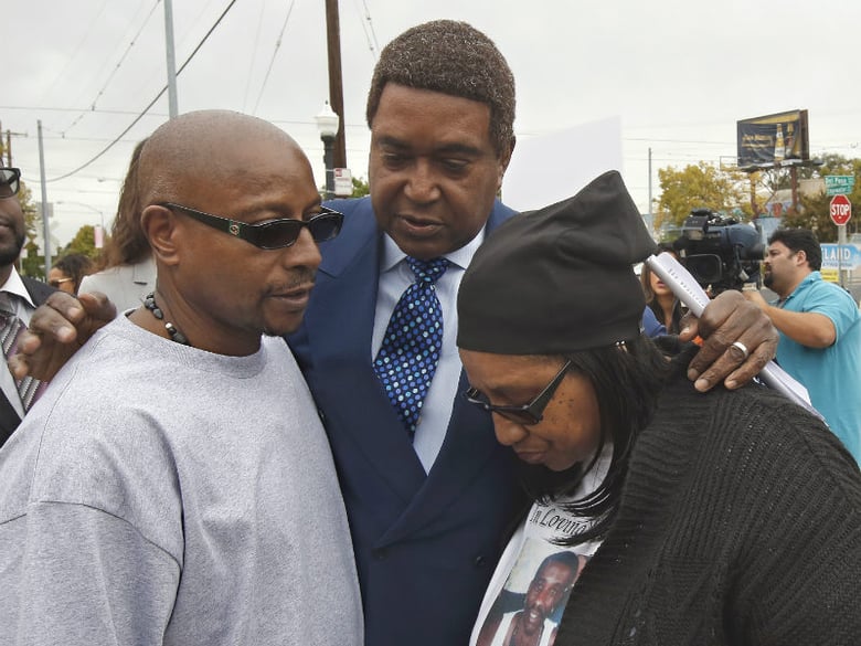 Attorney John Burris, center, comforts Robert and Deborah Mann, family members of Joseph Mann, who was killed by Sacramento Police in July, after a news conference Monday, Oct. 3, 2016, in Sacramento, Calif. 